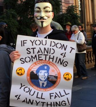 Photo of masked man with poster &quot;If you don&#039;t stand 4 something, you&#039;ll fall 4 anything.&quot;